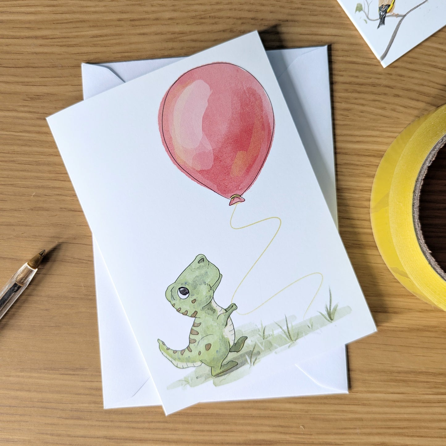this boys dinosaur birthday card features a little t-rex holding a big red balloon