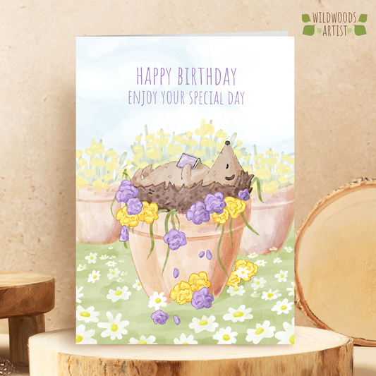 Hedgehog Birthday Card, featuring a watercolour illustration of a hedgehog sleeping in a plant pot, whilst reading a book.