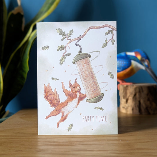 red squirrel birthday card featuring a red squirrel hanging off a bird feeder with the message 'party time!'